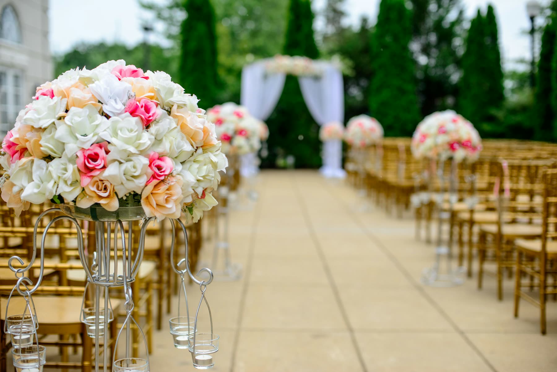 Wedding aisle lined with white and blush rose arrangements on tall stands