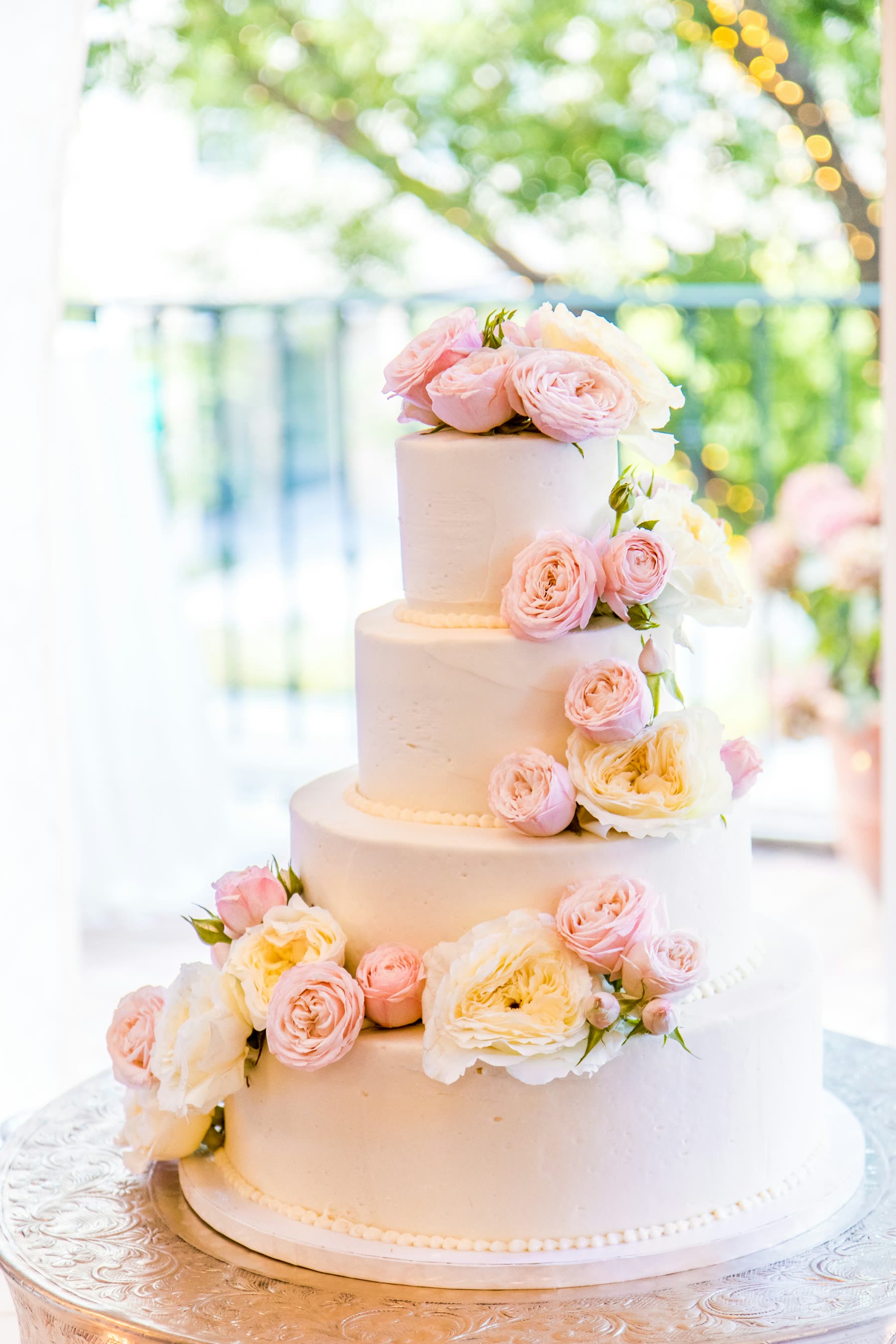 Tiered white wedding cake decorated with fresh white and blush roses
