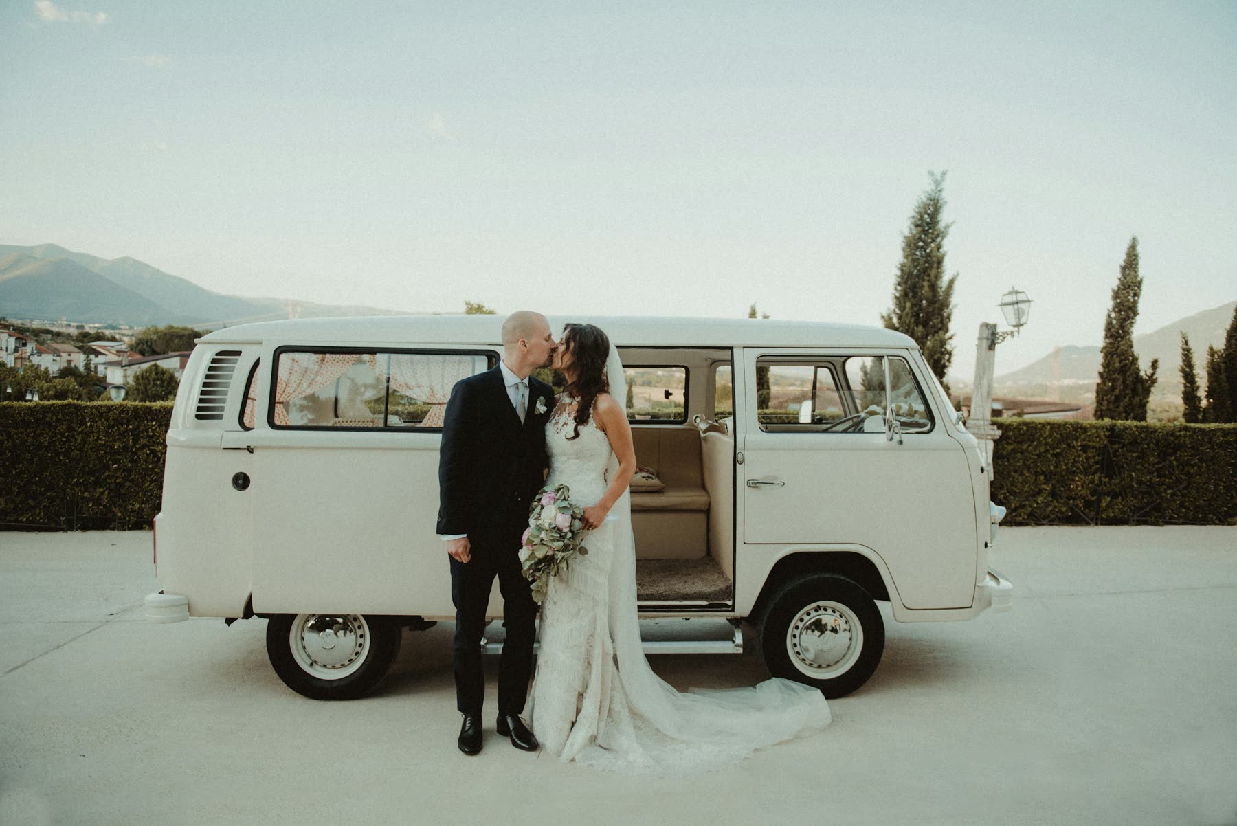 Newlyweds beside a white wedding getaway vehicle