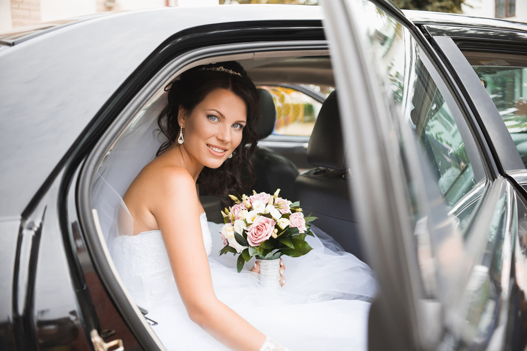 Bride holding her bouquet inside a black wedding limousine