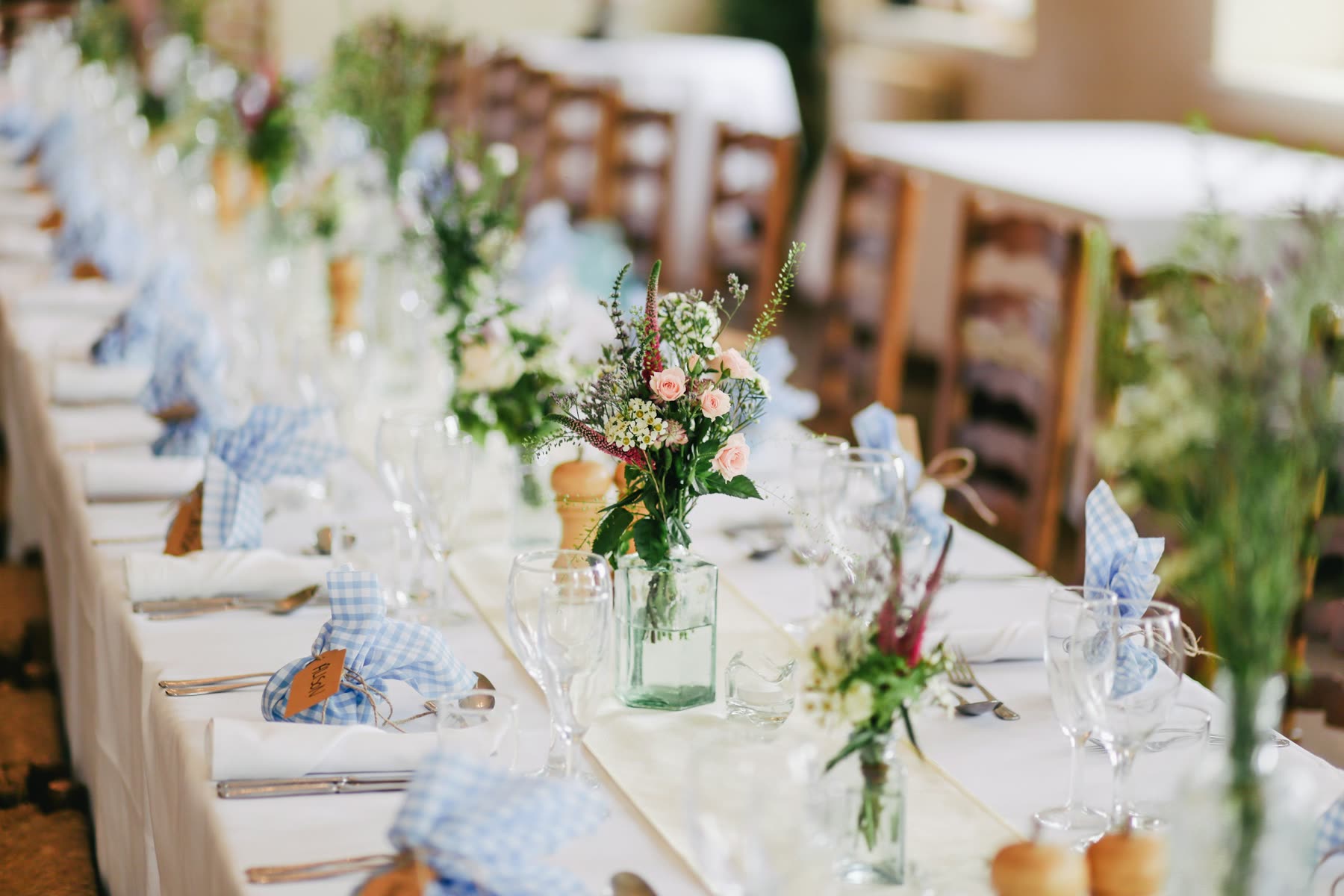 Long reception table set with white linens and low floral centrepieces